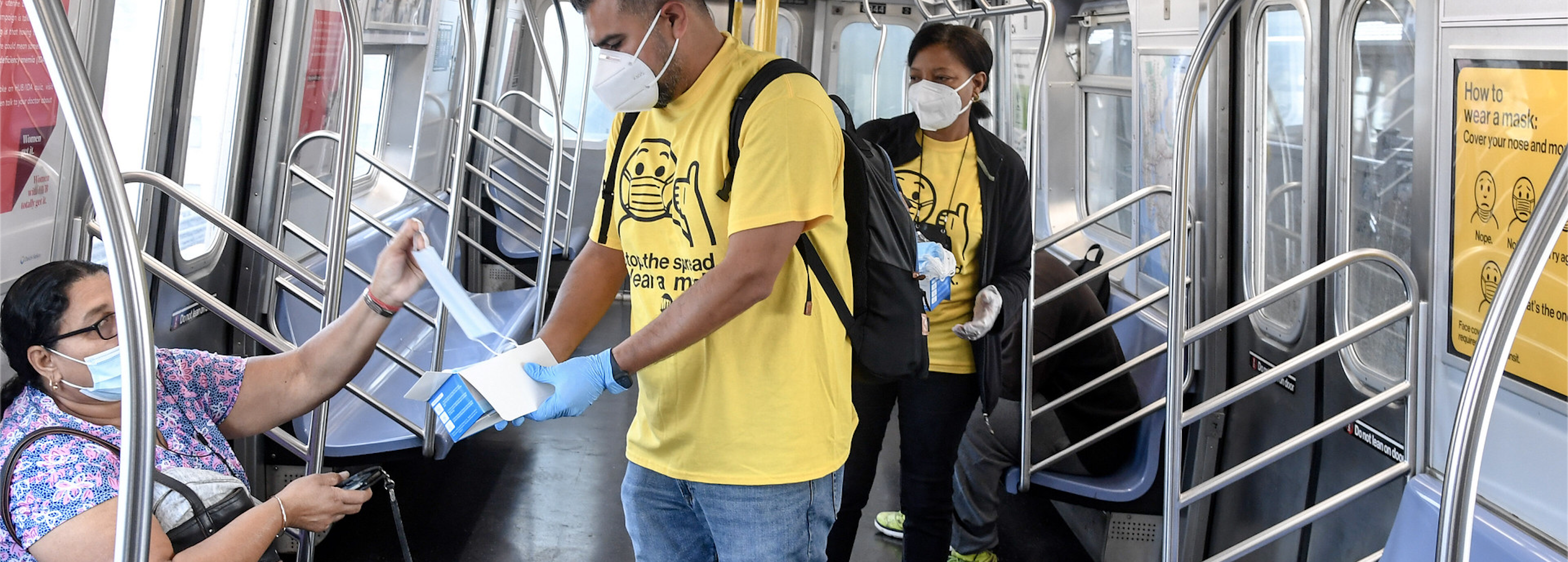 Mask Force Volunteers in yellow tshirts handing out masks to subway rider