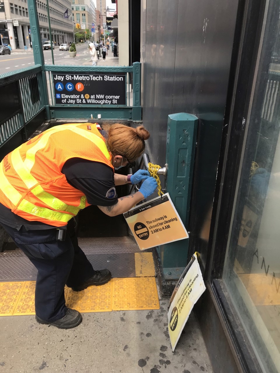 Shanica Godfrey, a station booth agent at the Columbus Circle station, removes an overnight closure sign.
