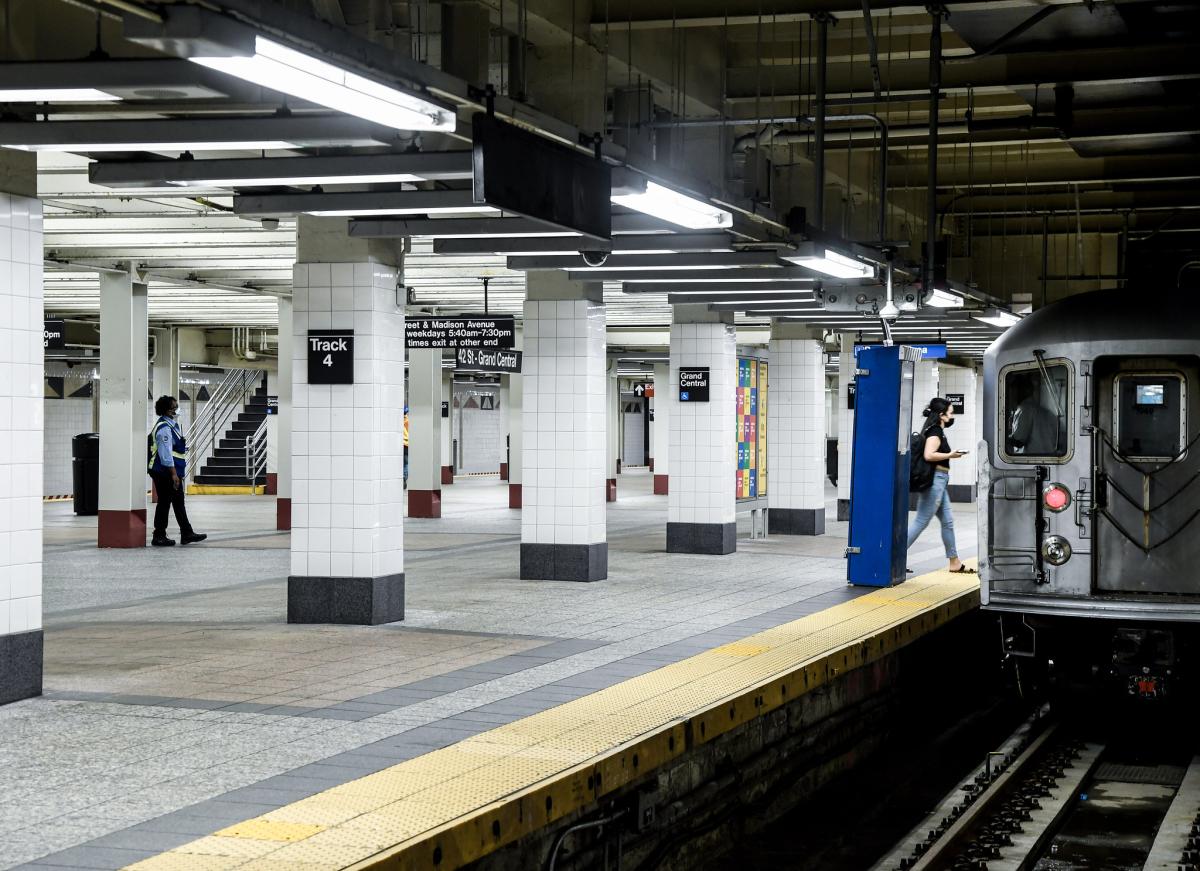 A renovated subway platform with people boarding a train. 