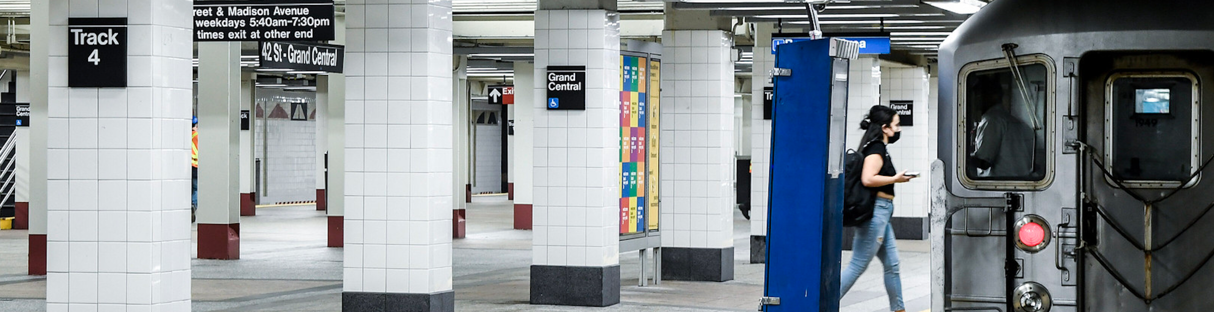 A subway platform with a woman boarding a train.