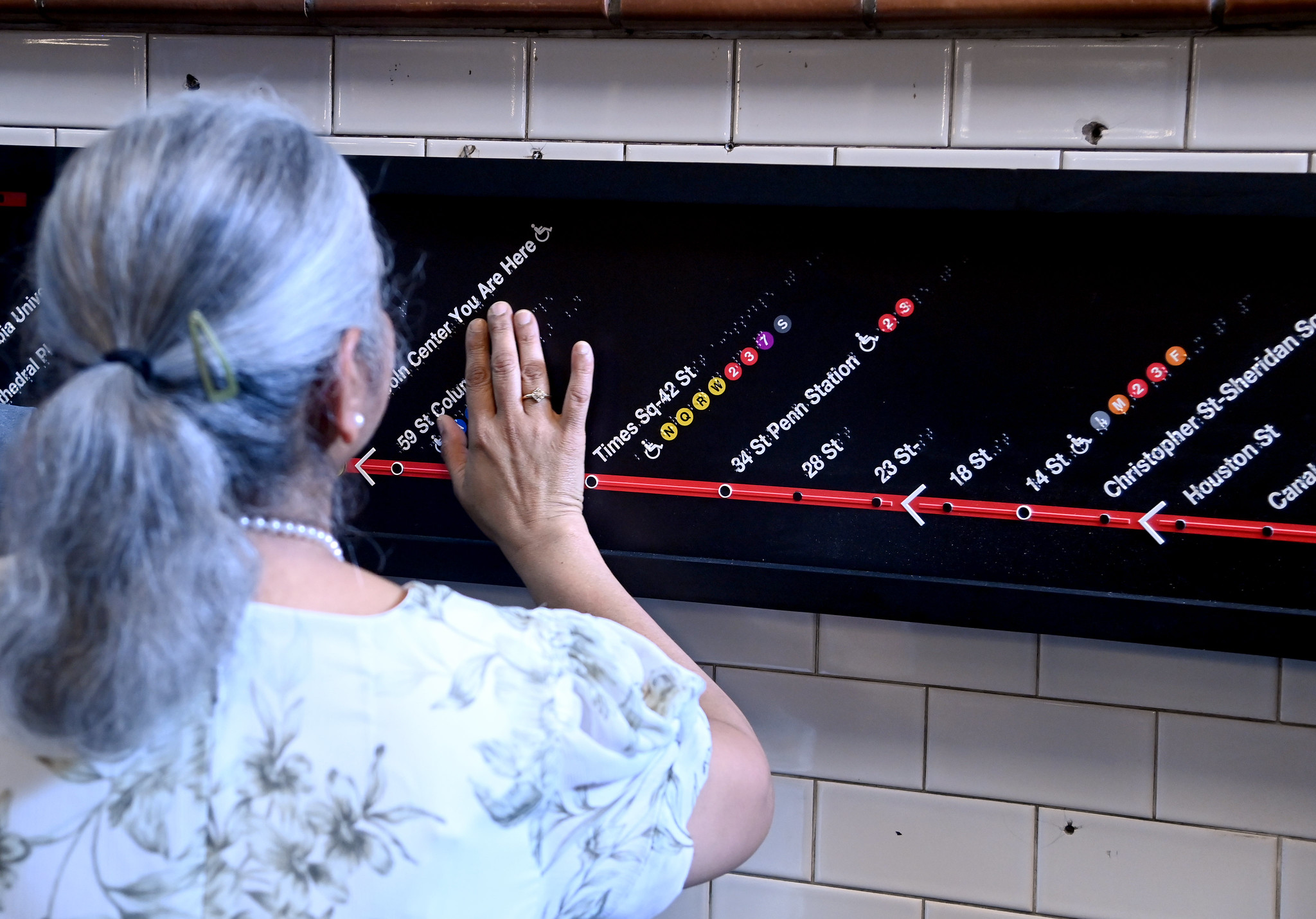 View from behind of woman touching the braille tactile line map.